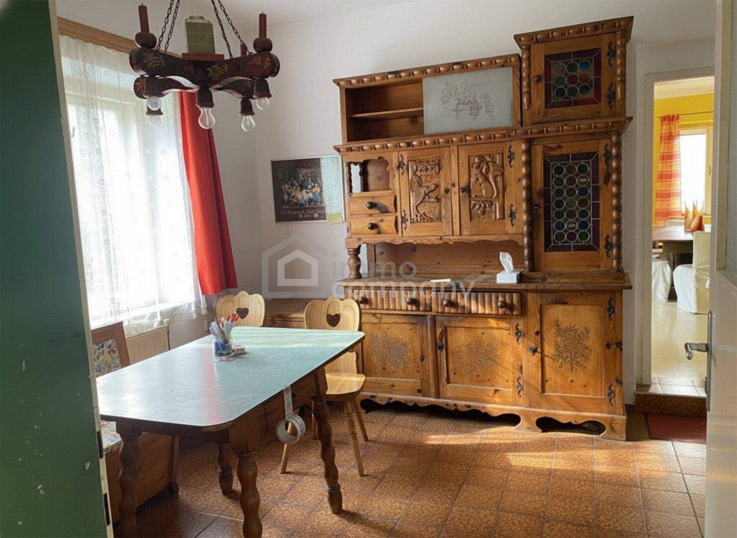 Traditioneller Essbereich mit rustikalen Holzmöbeln, Kronleuchter und Blick in den Garten.