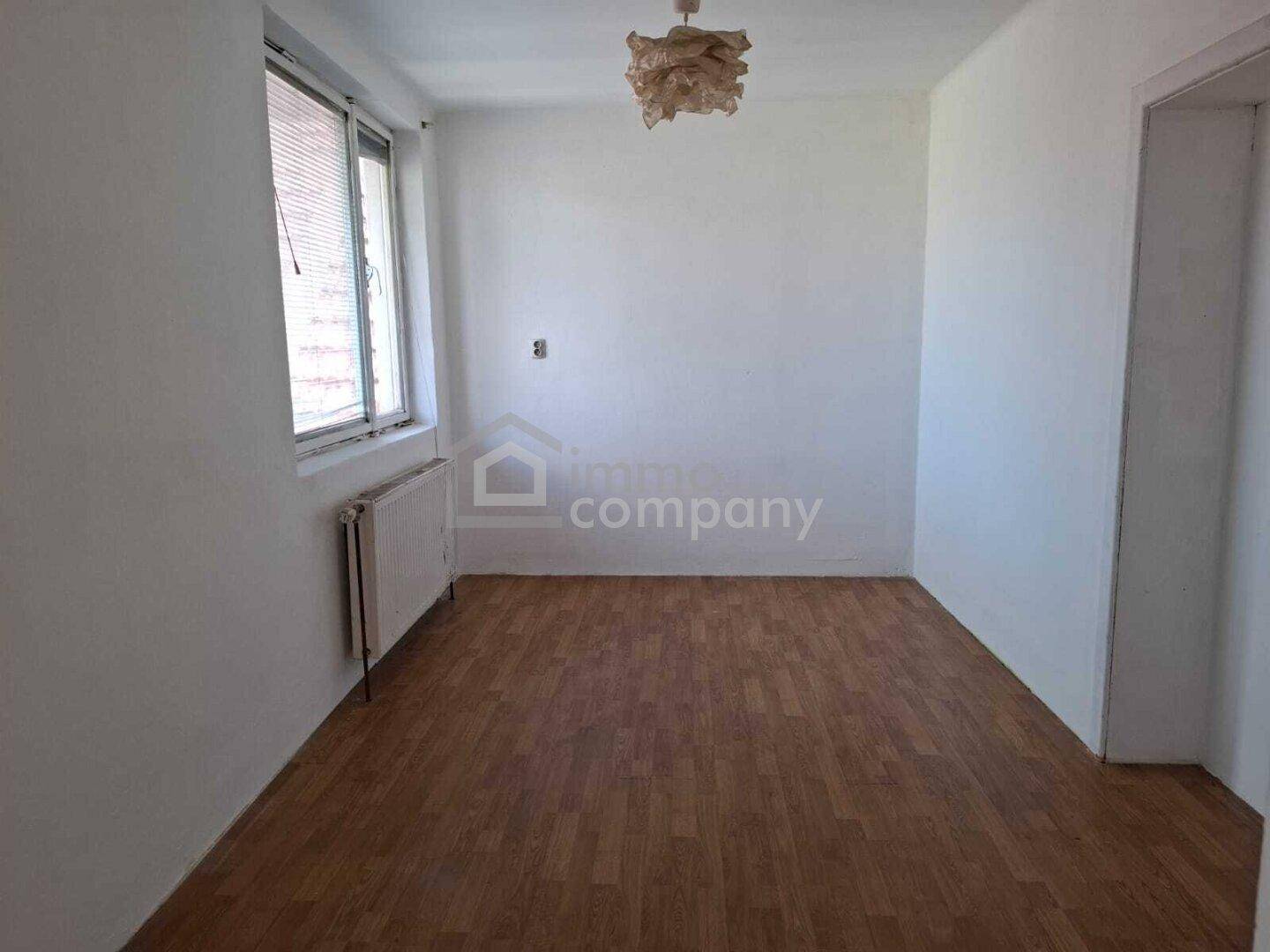 Leeres Schlafzimmer mit Laminatboden und Fenster, bereit zur Einrichtung.