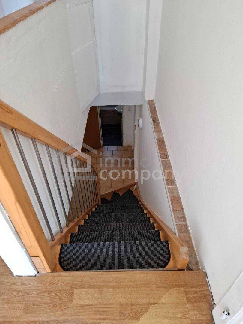 Blick von oben auf eine Holztreppe mit dunklem Teppichbelag.