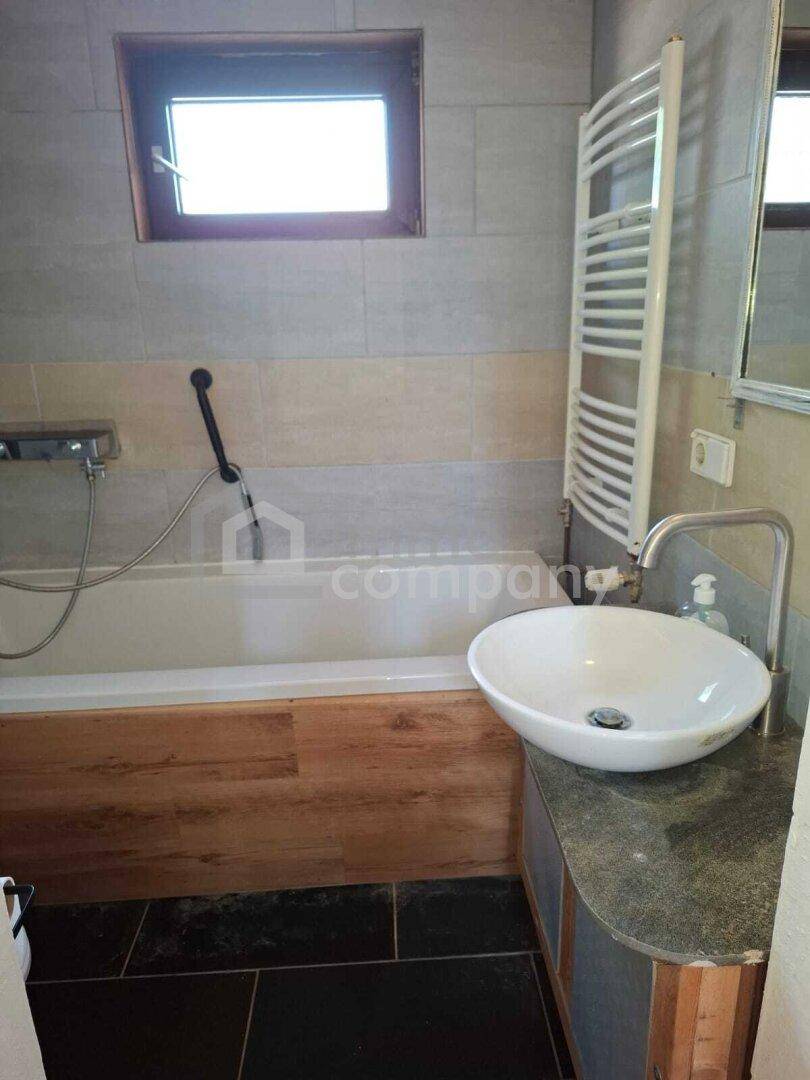 Badezimmer mit Badewanne, Aufsatzwaschbecken und Fliesen an den Wänden.