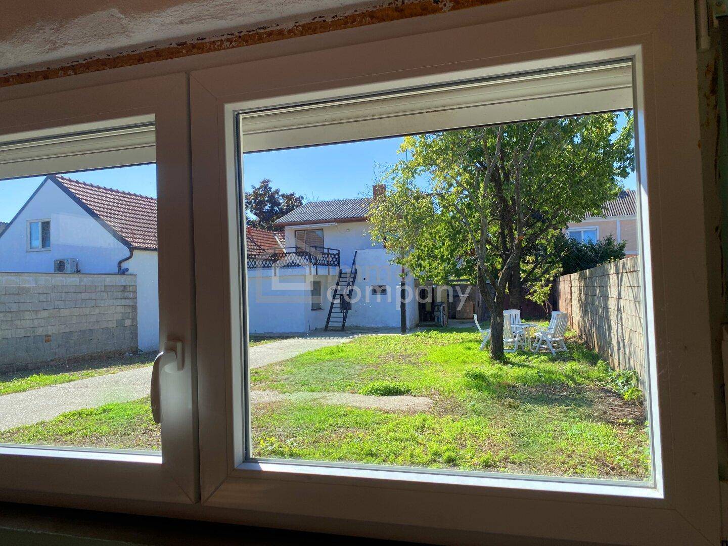 Blick aus dem Fenster auf den Gartenbereich mit Rasen und Bäumen.