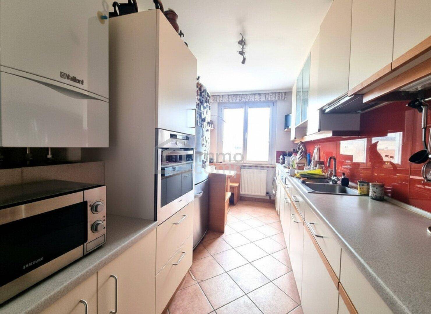 Funktionale Küche mit Fliesenboden, Einbaugeräten und Fenster für Tageslicht.