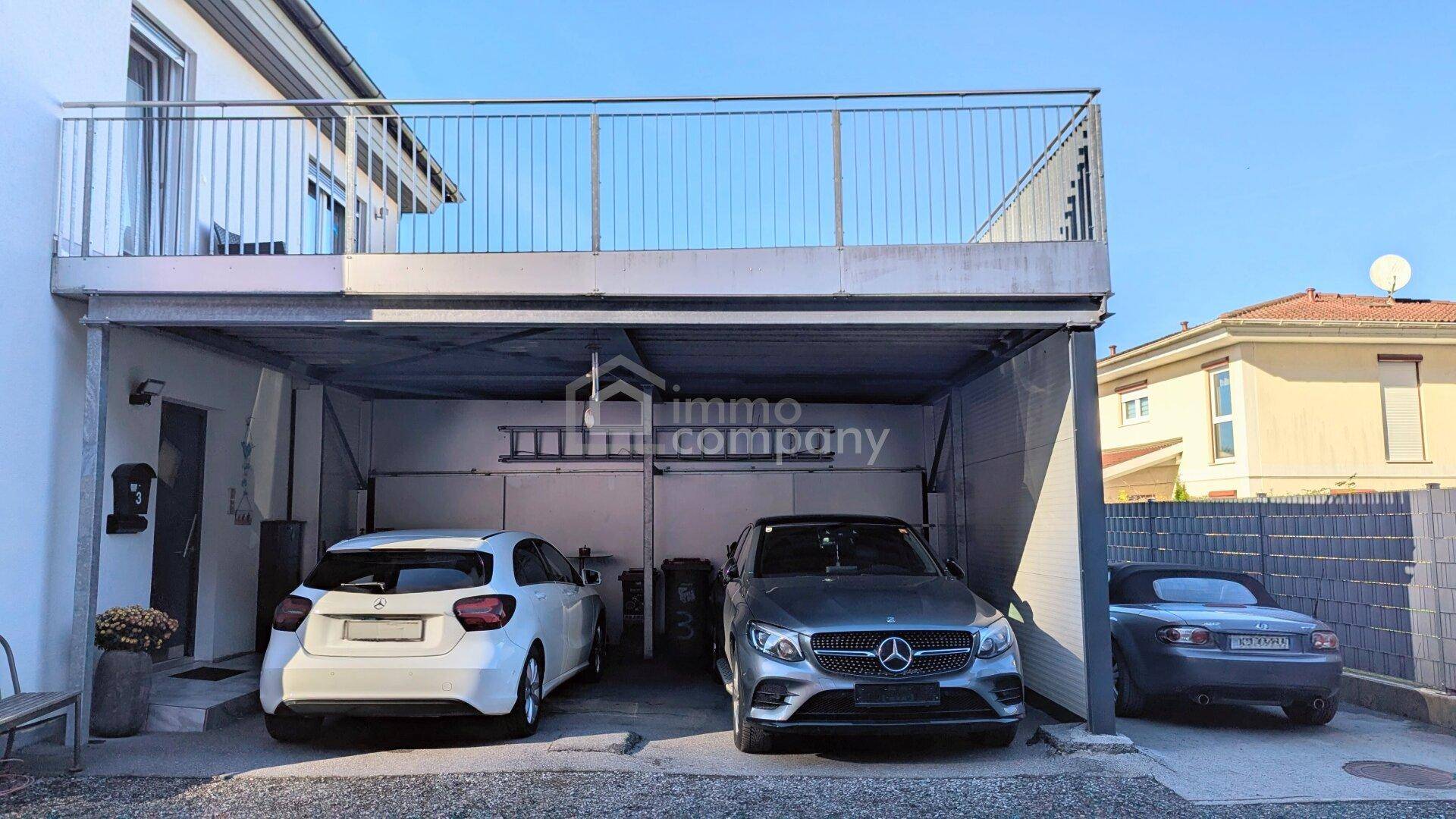 Überdachter Parkplatz für zwei Fahrzeuge unter einer Terrasse, mit direktem Zugang.