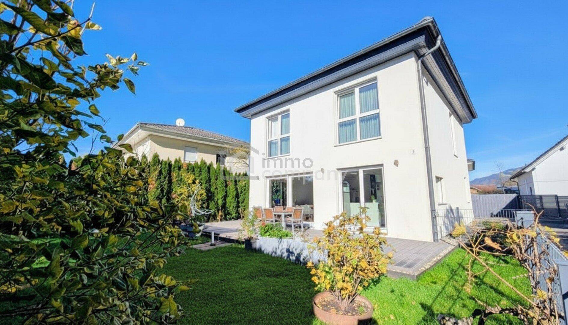 Freistehendes Einfamilienhaus mit Terrasse und gepflegtem Garten, umgeben von hohen Hecken für Privatsphäre.