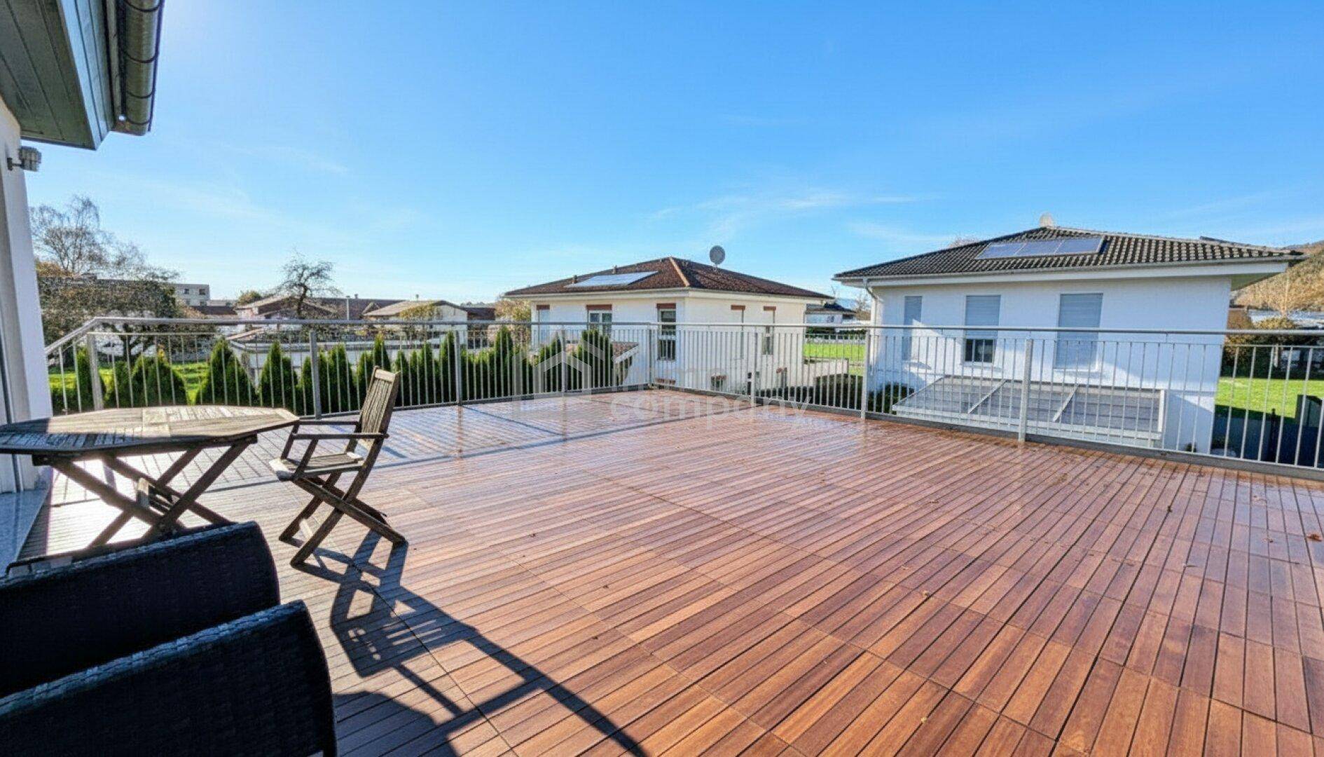 Geräumige Dachterrasse mit Holzboden und Metallgeländer, ideal zum Entspannen im Freien.