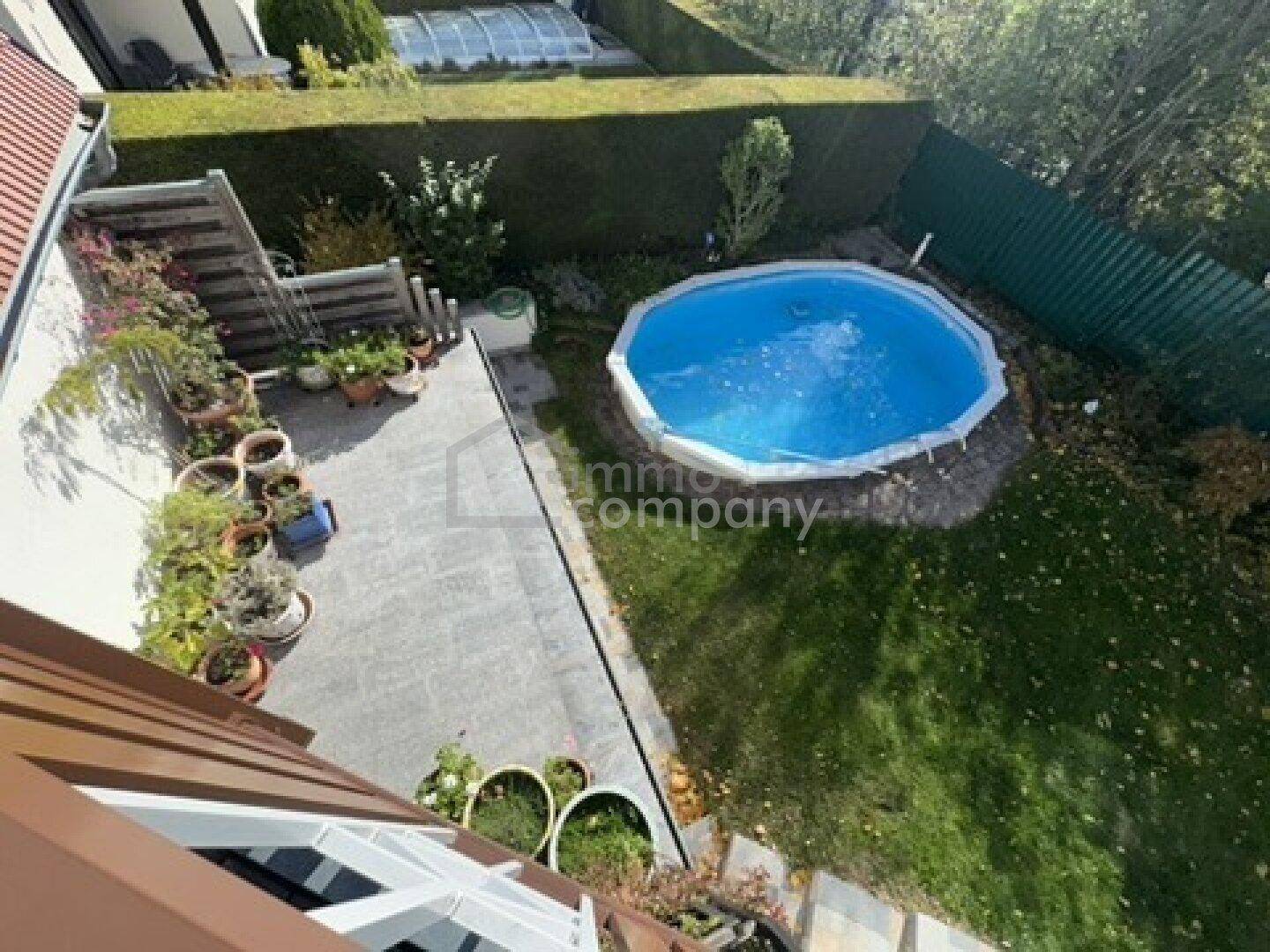 Überblick über den Garten mit Aufstellpool, Rasenfläche und gepflastertem Sitzbereich.