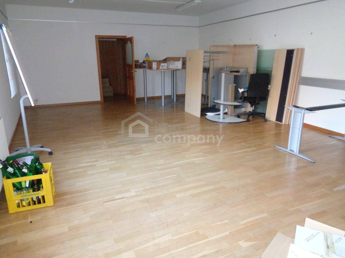 Großer, heller Büroraum mit Holzboden und verschiedenen Büromöbeln und Materialien.