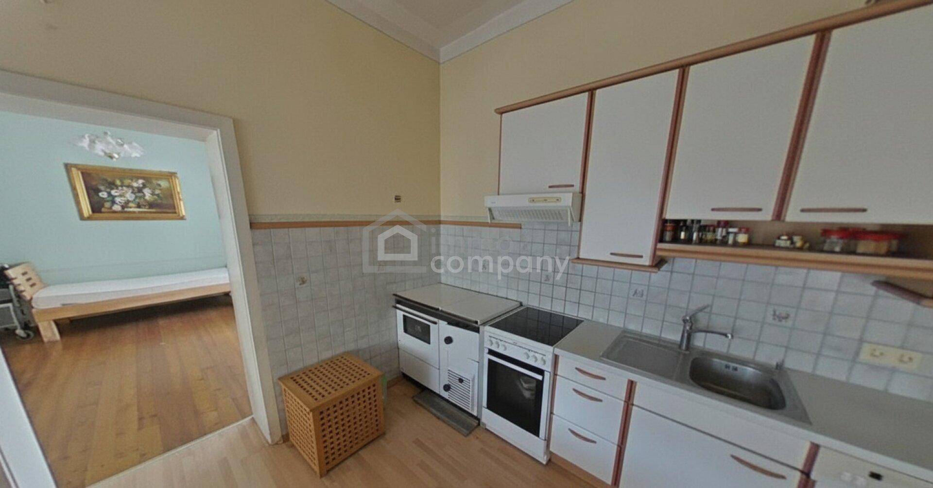 Funktionale Küche mit weißen Schränken, gefliestem Spritzschutz und einem traditionellen Holzofen.