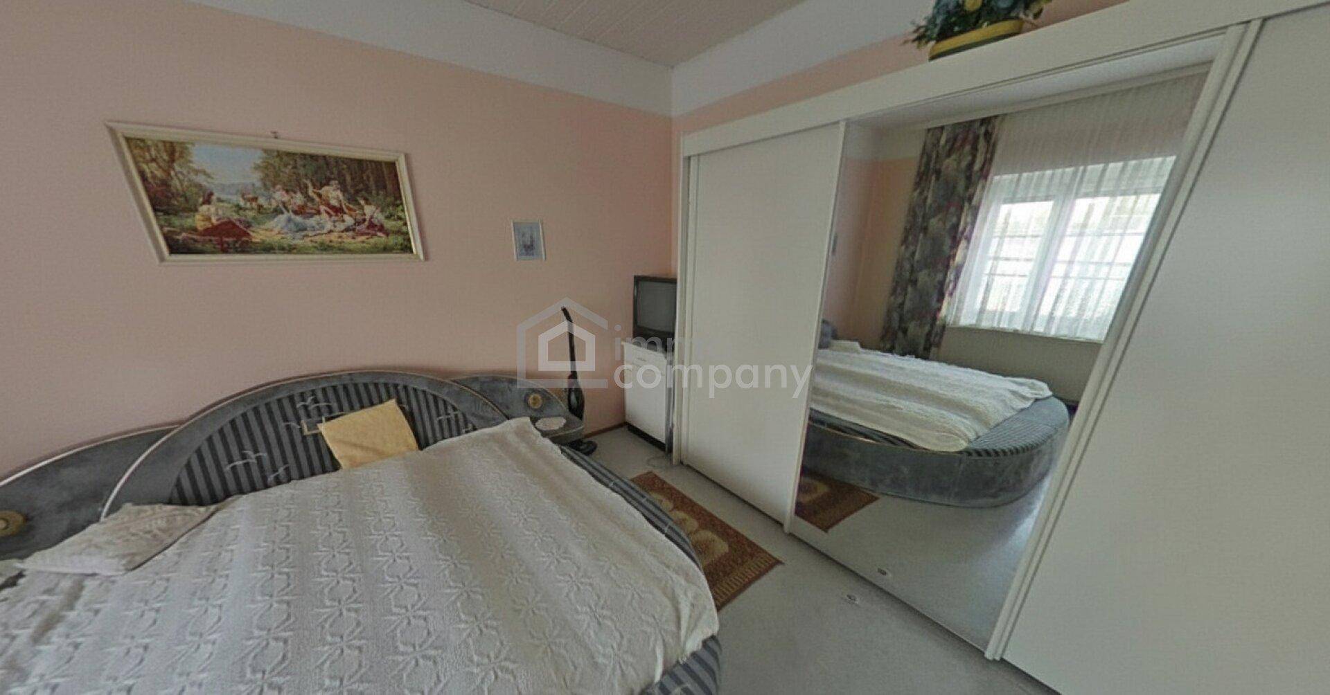 Schlafzimmer mit einem runden Bett, großem Spiegelschrank und rosa gestrichenen Wänden.