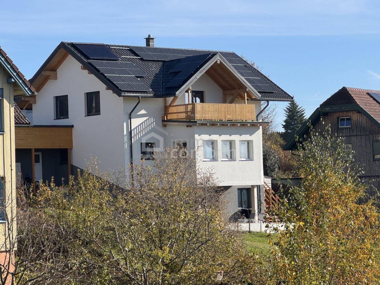 Das moderne Wohnhaus mit Satteldach und Photovoltaikanlage, umgeben von herbstlicher Vegetation.