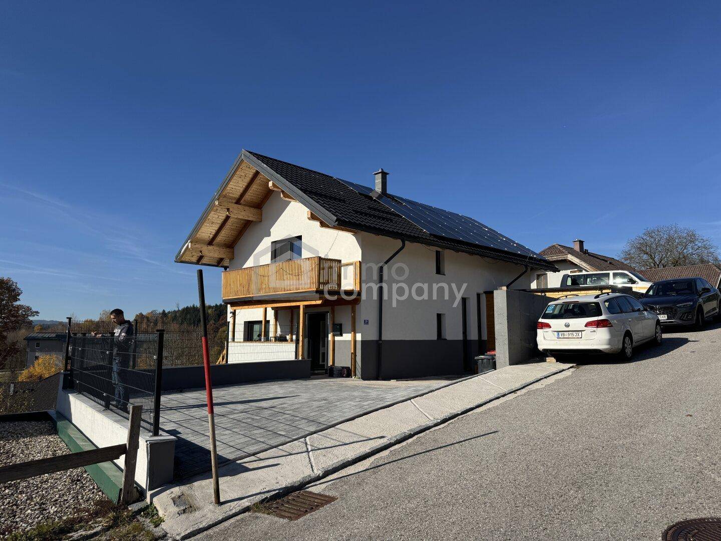 Ansicht des modernen Hauses von der Straße mit Photovoltaikanlage, Auffahrt und Parkplätzen.