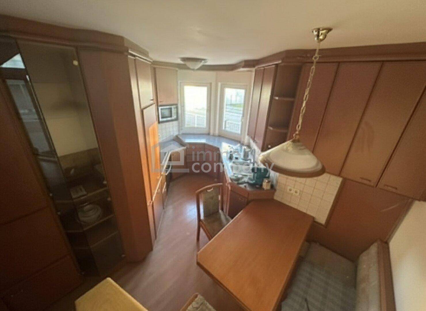 Küche im traditionellen Stil mit Holzschränken, integrierten Geräten und einem kleinen Essbereich.