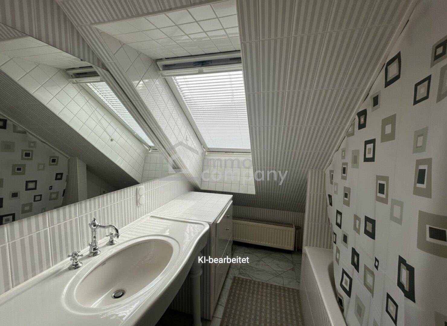 Badezimmer im Dachgeschoss mit Badewanne, Waschbecken und Dachfenster, ausgestattet mit Fliesen.