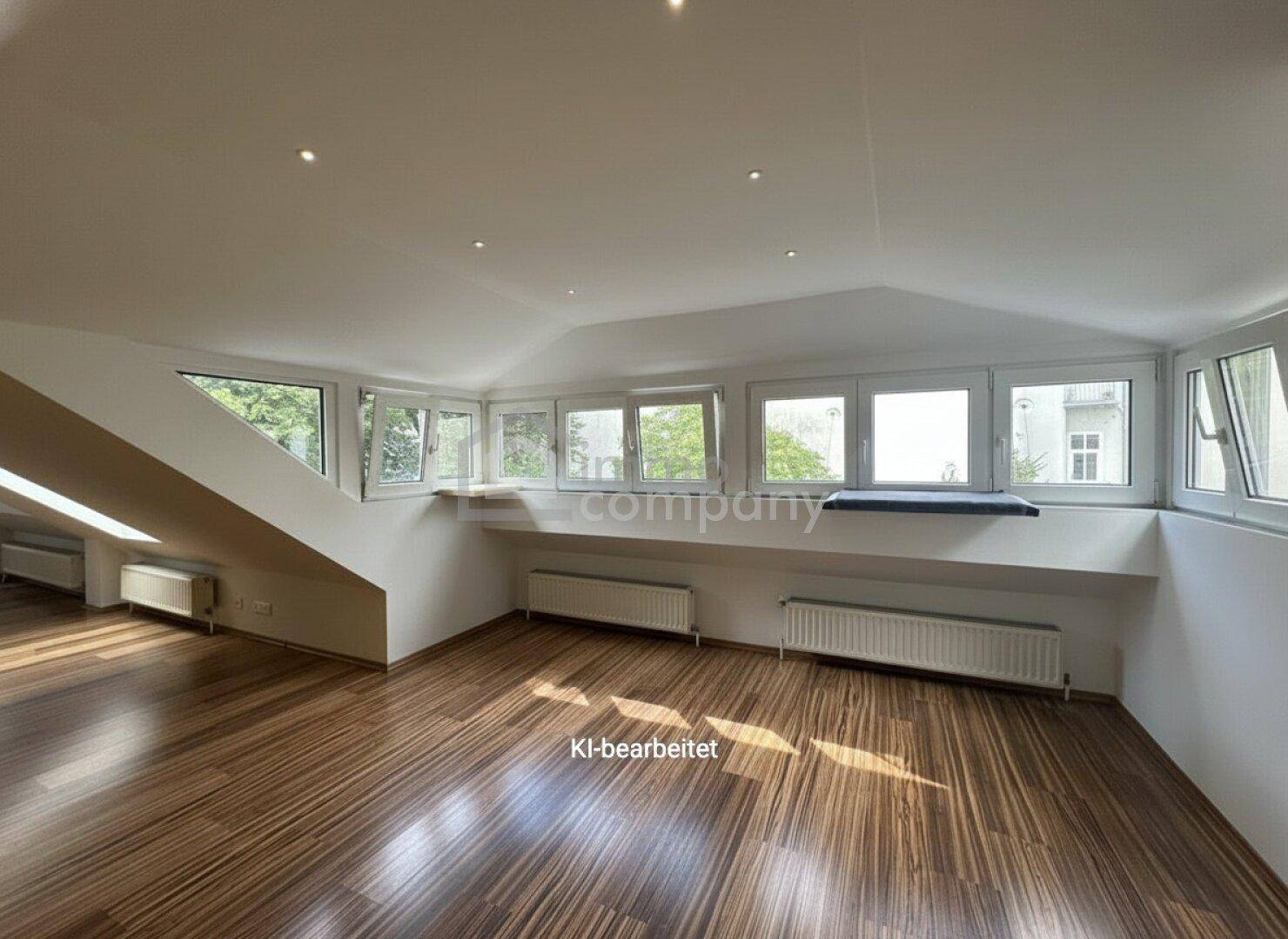 Geräumiger, heller Raum im Dachgeschoss mit Holzboden und einer Fensterfront, ideal für flexible Nutzung.