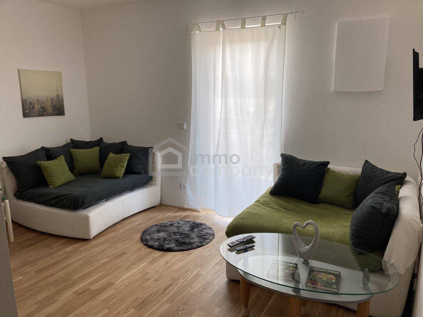 Gemütliches Wohnzimmer mit zwei Sofas, einem Glastisch und hellem Holzboden.