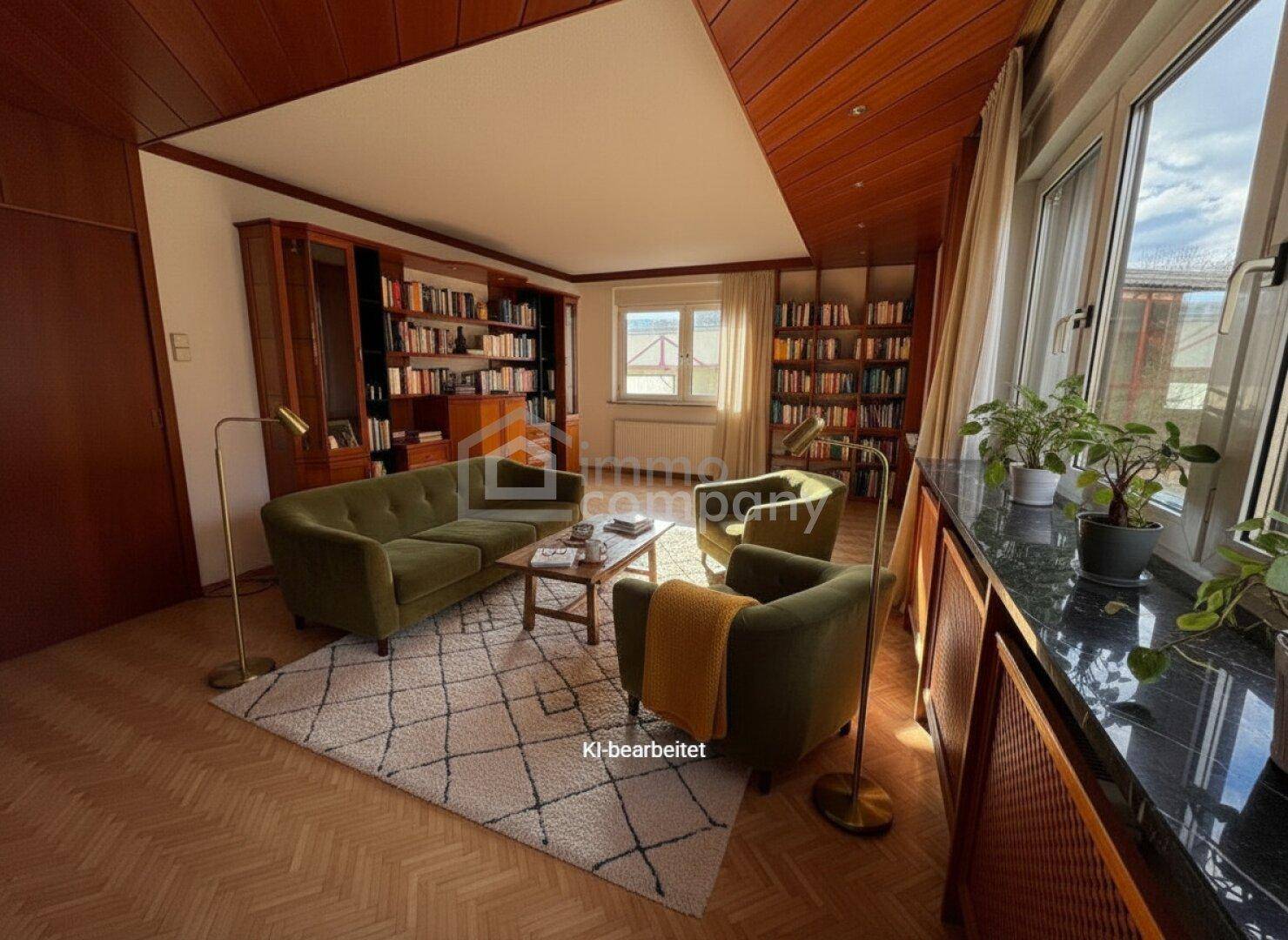 Gemütliches Wohnzimmer mit Holzdecke, Parkettboden, Bücherregalen und Blick ins Grüne.