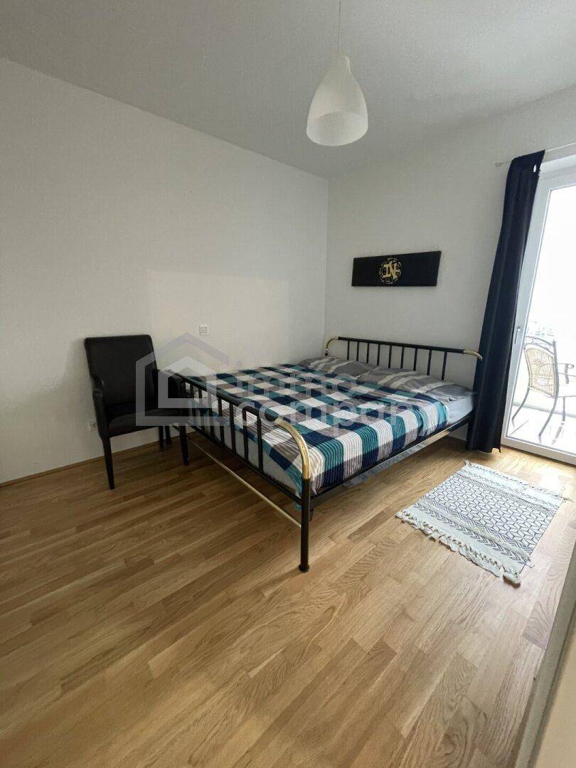 Schlafzimmer mit Doppelbett, Holzfußboden und direktem Zugang zu einem Balkon.