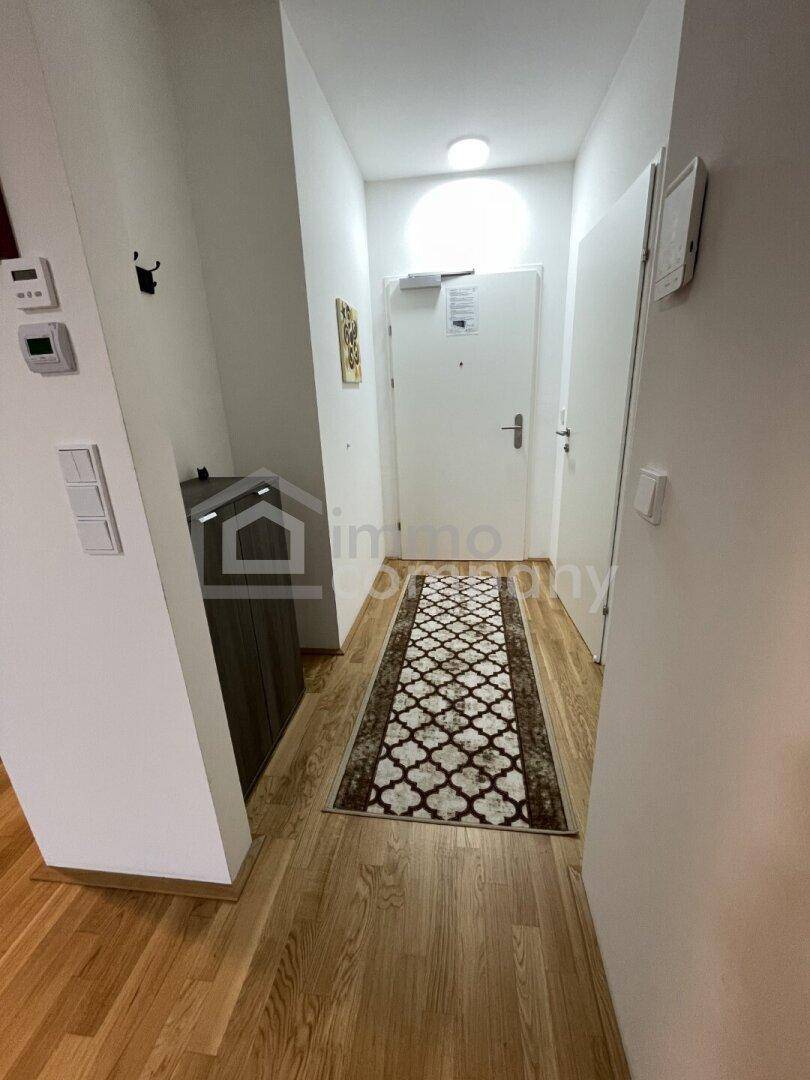 Geräumiger Flur mit Holzfußboden und heller Beleuchtung, der den Zugang zu den Räumen ermöglicht.