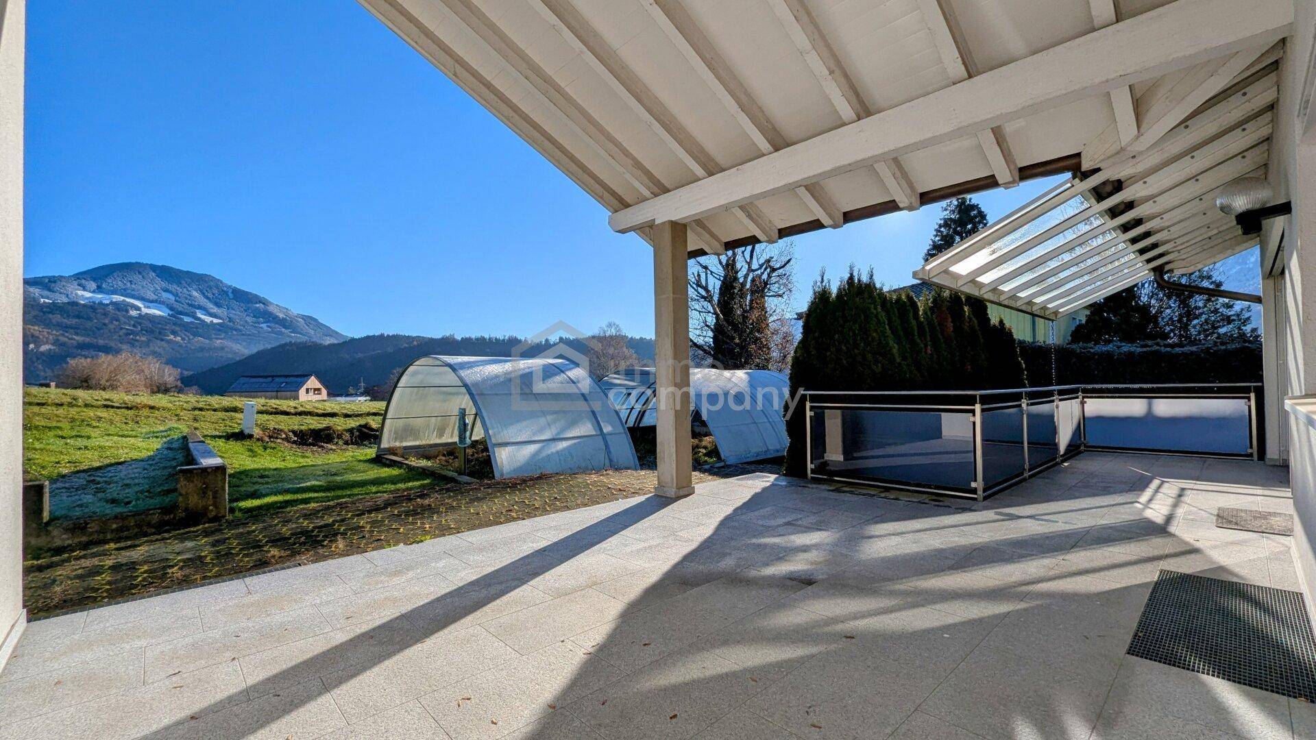Geräumige überdachte Terrasse mit Fliesenboden und weitem Blick auf die Natur.