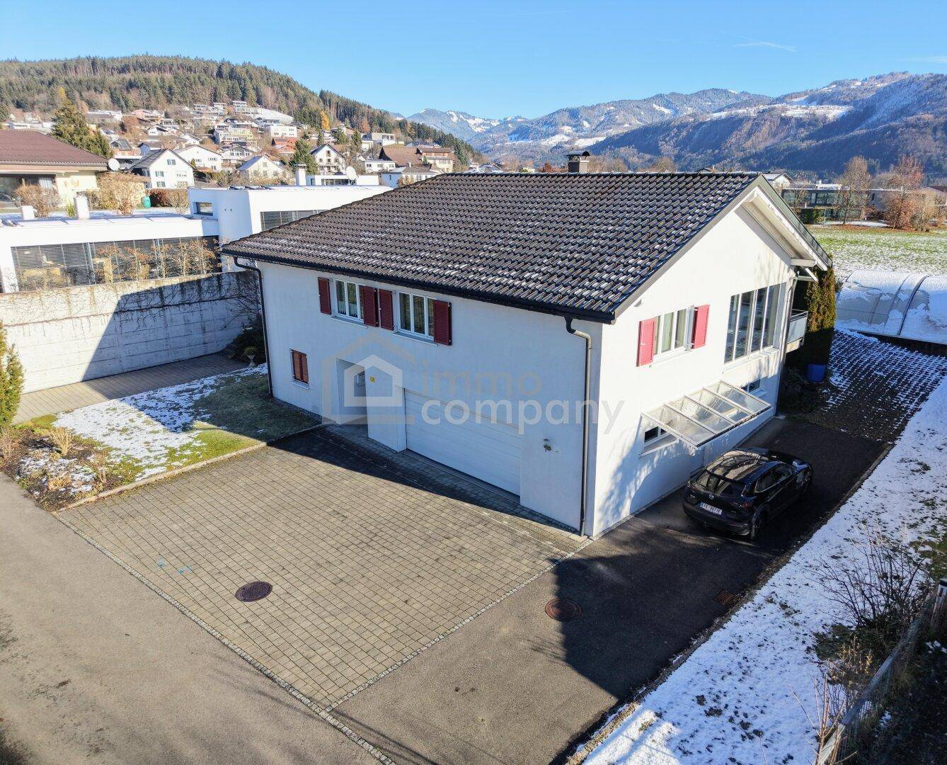 Vorderansicht des Hauses mit gepflasterter Einfahrt und roten Fensterläden.