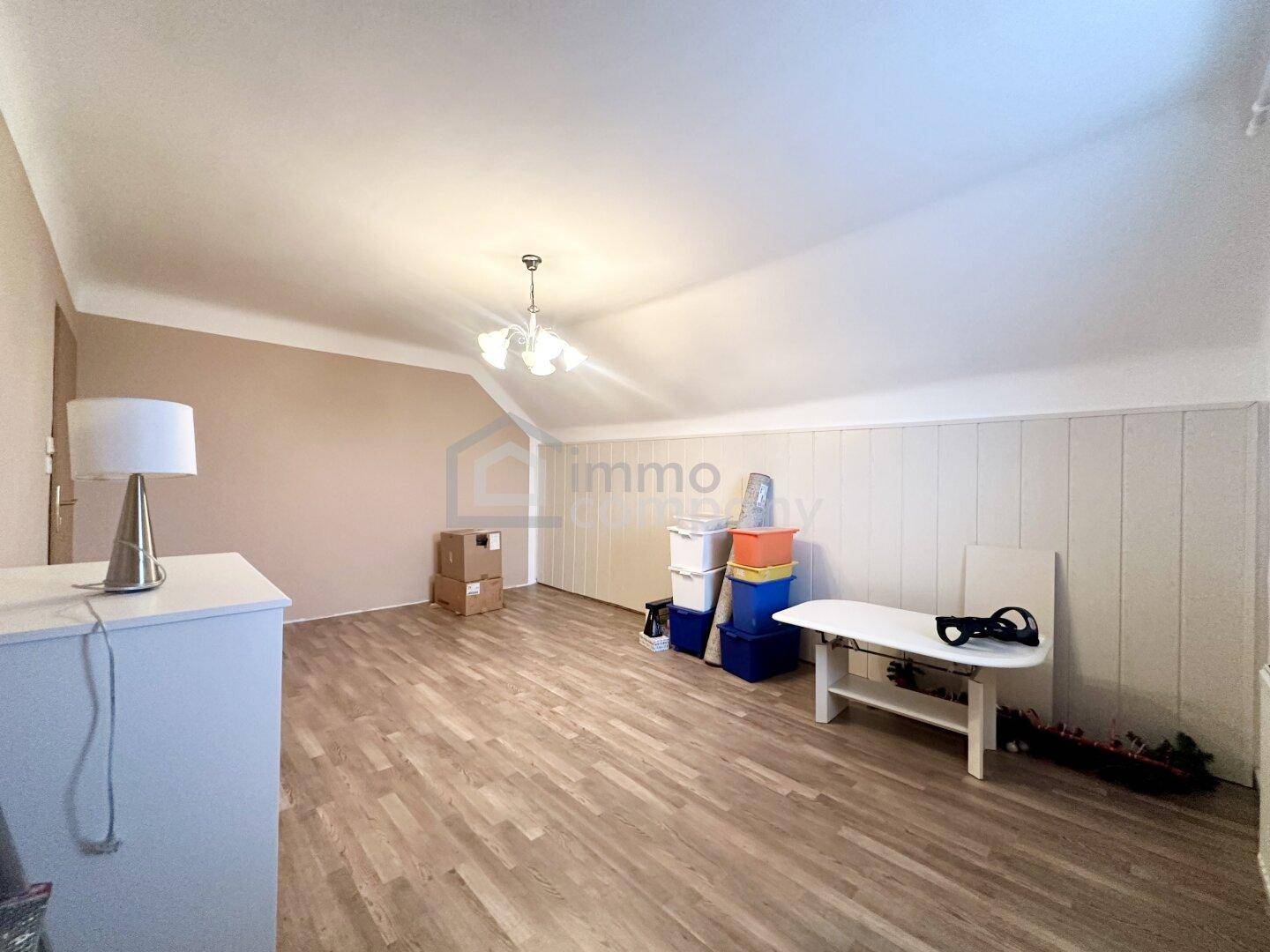 Dachzimmer mit Laminatboden und schrägen Wänden, bereit zur individuellen Gestaltung.