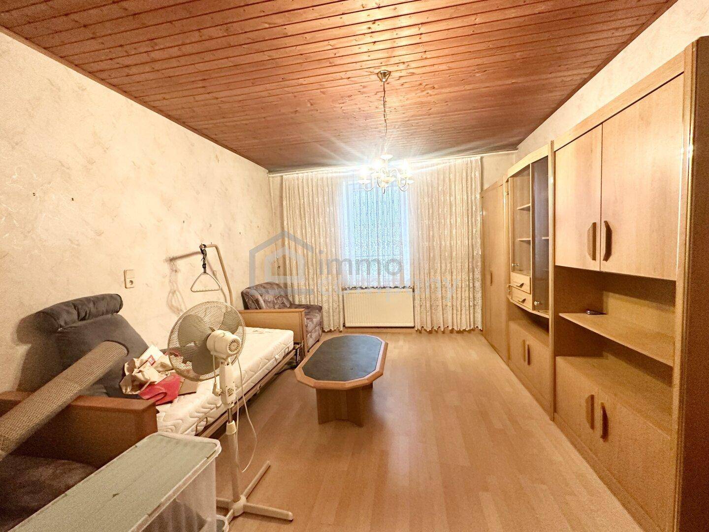 Gemütliches Wohnzimmer mit Holzdecke, Parkettboden und traditionellen Möbeln.