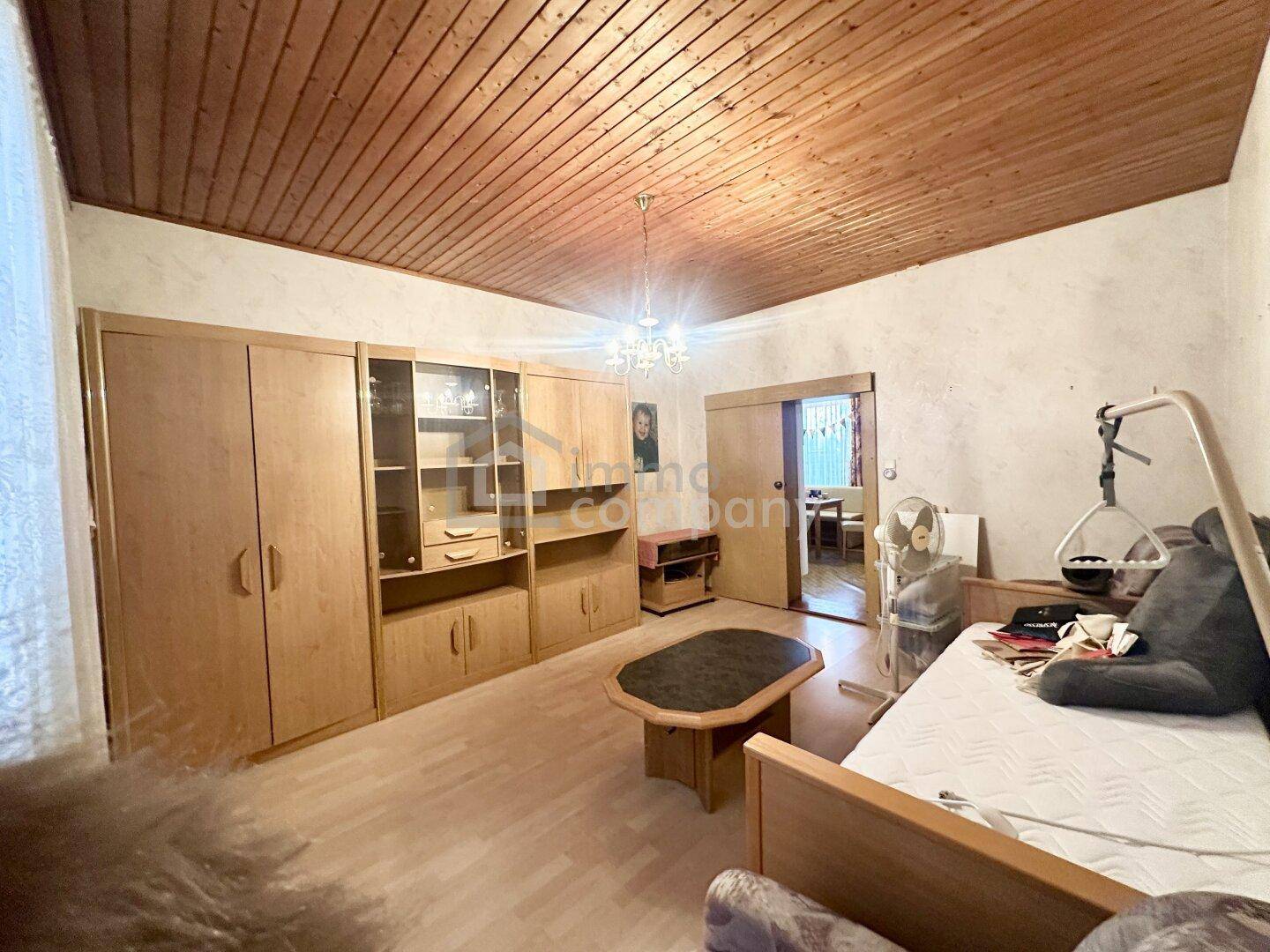 Wohnzimmer mit Holzdecke, Parkettboden und einem großen Schrankwand.