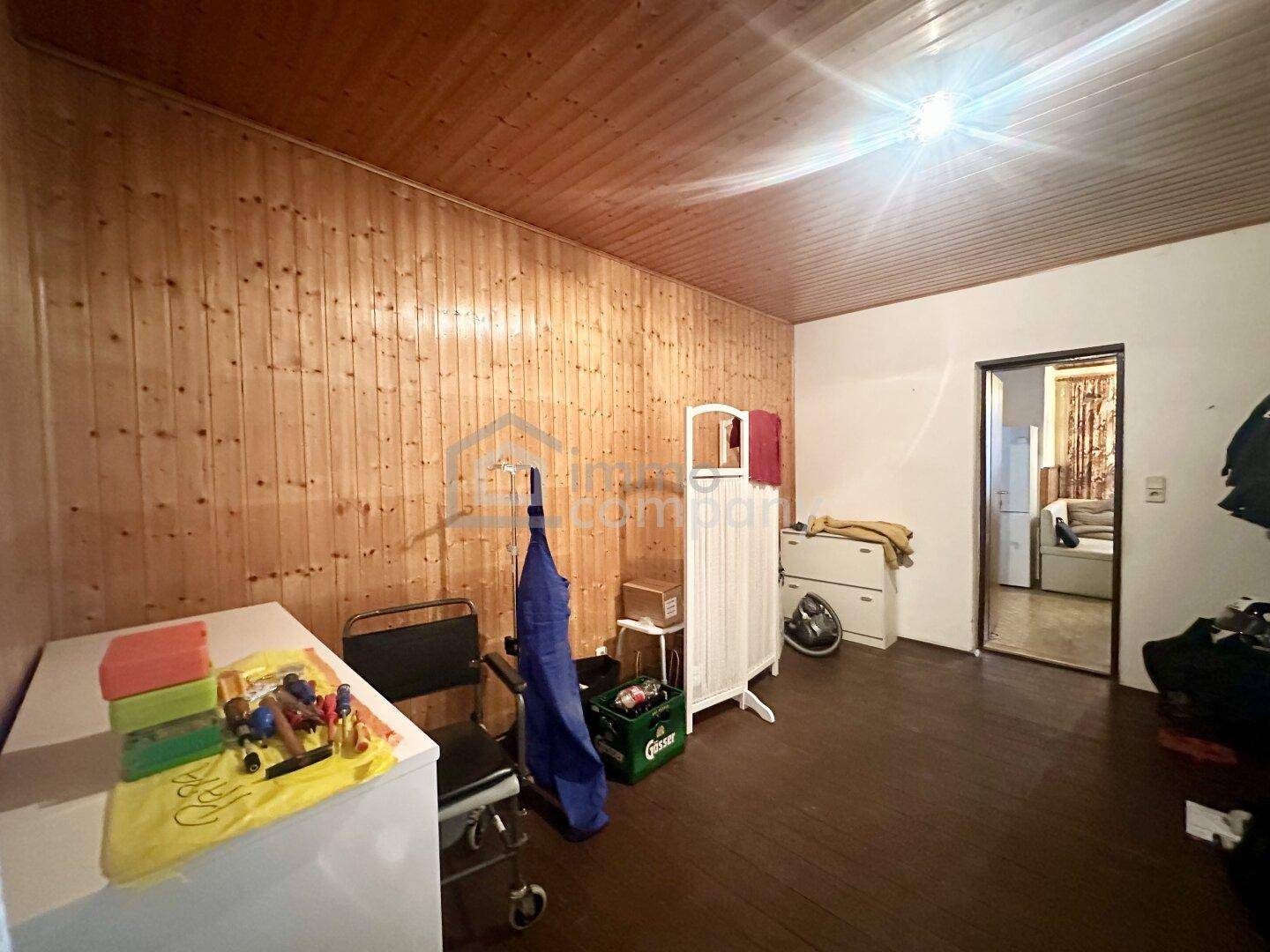 Zimmer mit Holzwandverkleidung, Holzdecke und dunklem Laminatboden.
