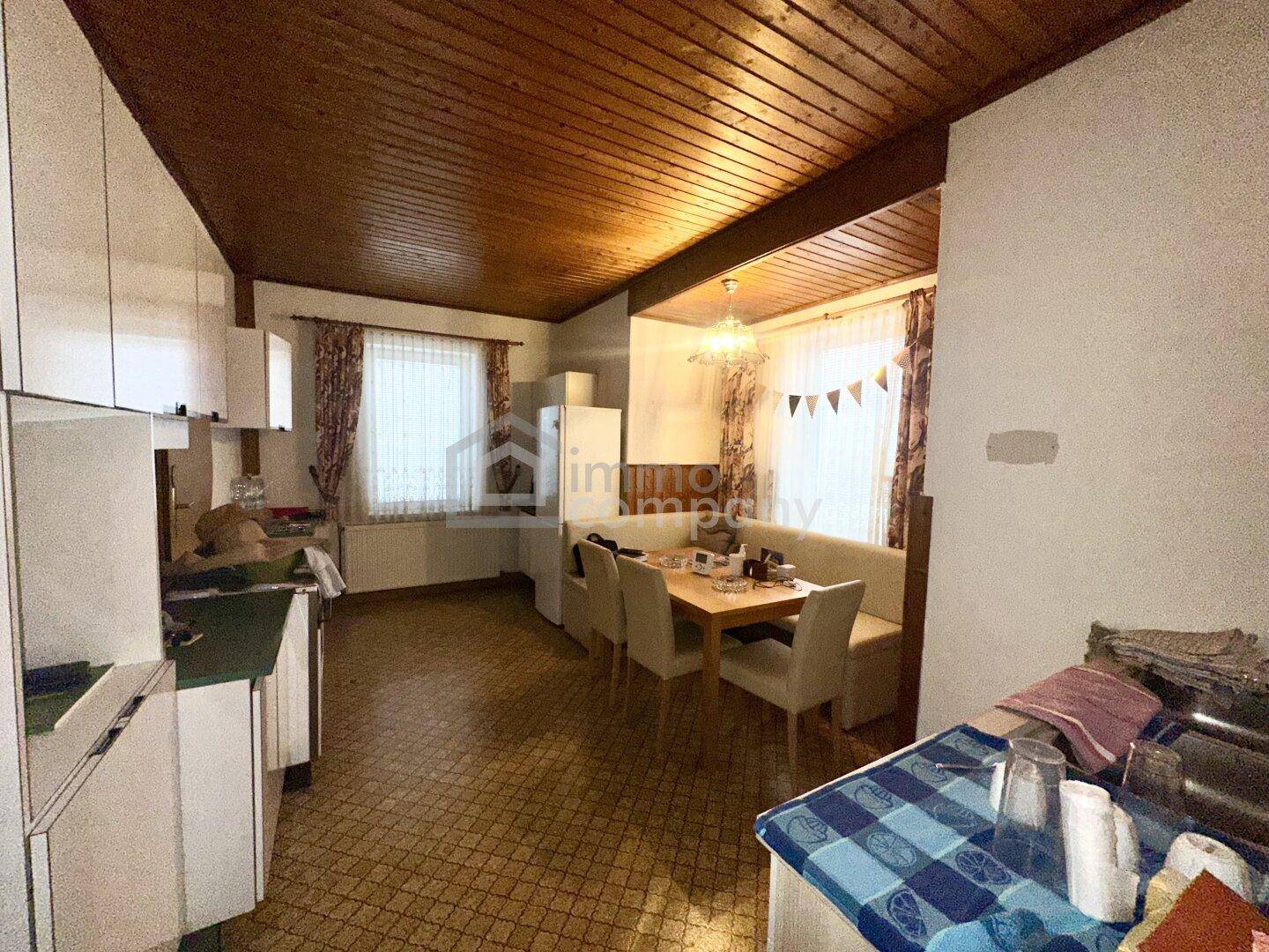 Geräumige Wohnküche mit Essbereich, Holzdecke und Blick nach draußen.