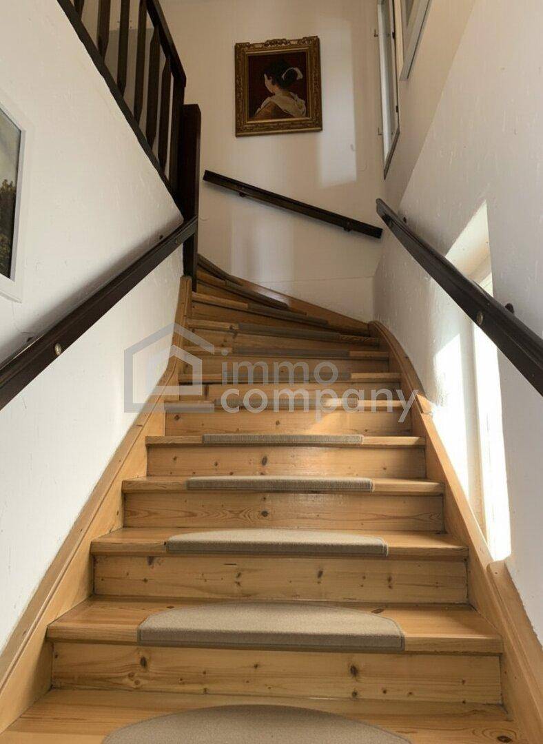 Holztreppe mit Teppichläufern und Handläufen, die zu den oberen Etagen führt.