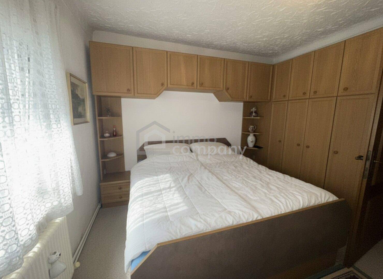 Schlafzimmer mit Einbauschränken, Doppelbett und Fenster für natürliches Licht.