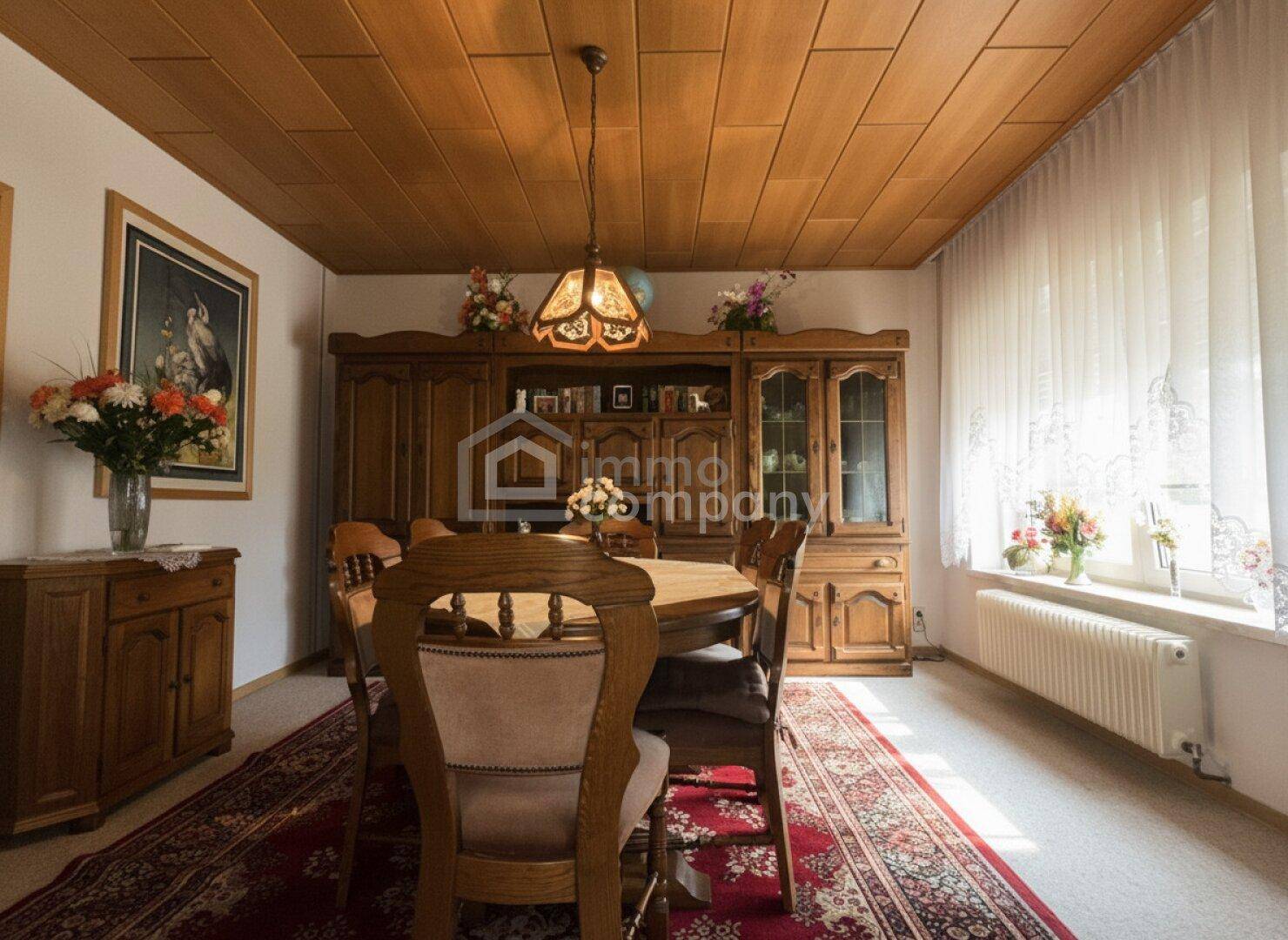 Traditioneller Essbereich mit großem Holztisch, passenden Stühlen und Holzpaneeldecke.