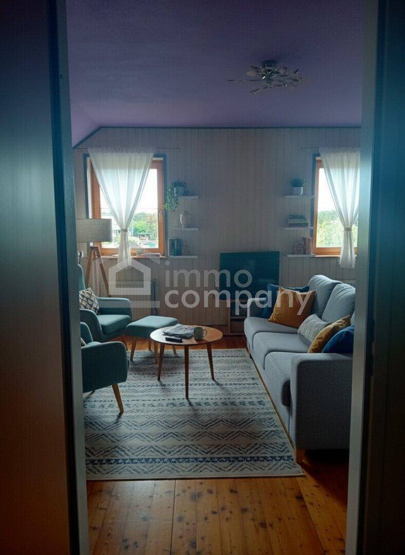 Gemütliches Wohnzimmer mit Holzboden, moderner Einrichtung und lila Decke, gut beleuchtet.