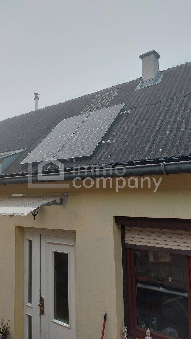 Dach des Gebäudes mit installierten Photovoltaikmodulen und einem Schornstein auf dem Satteldach.