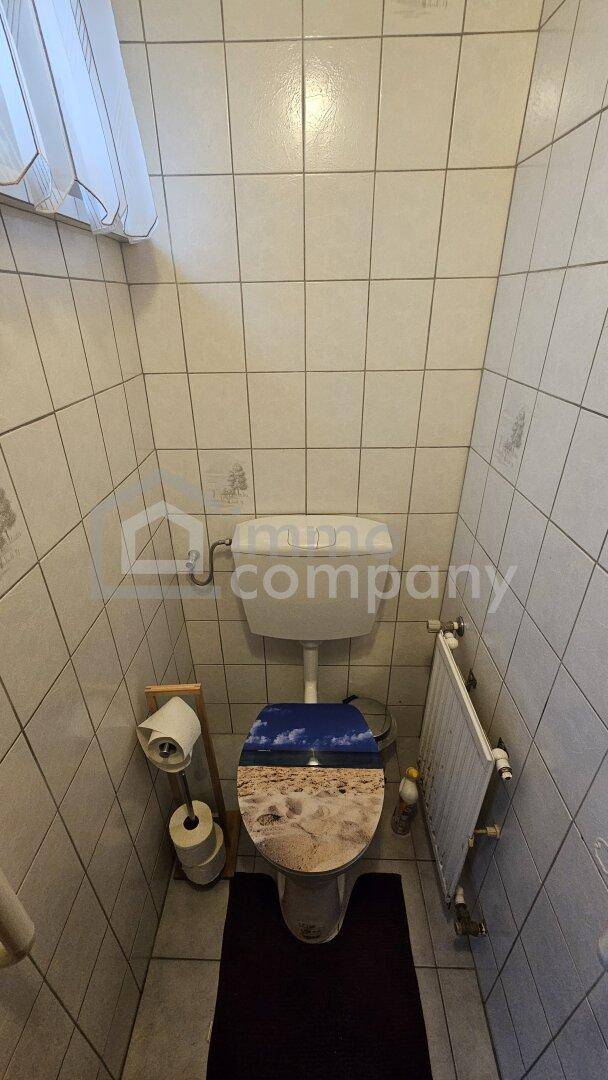 Kleines WC mit Fliesen an Wänden und Boden sowie einem Heizkörper.