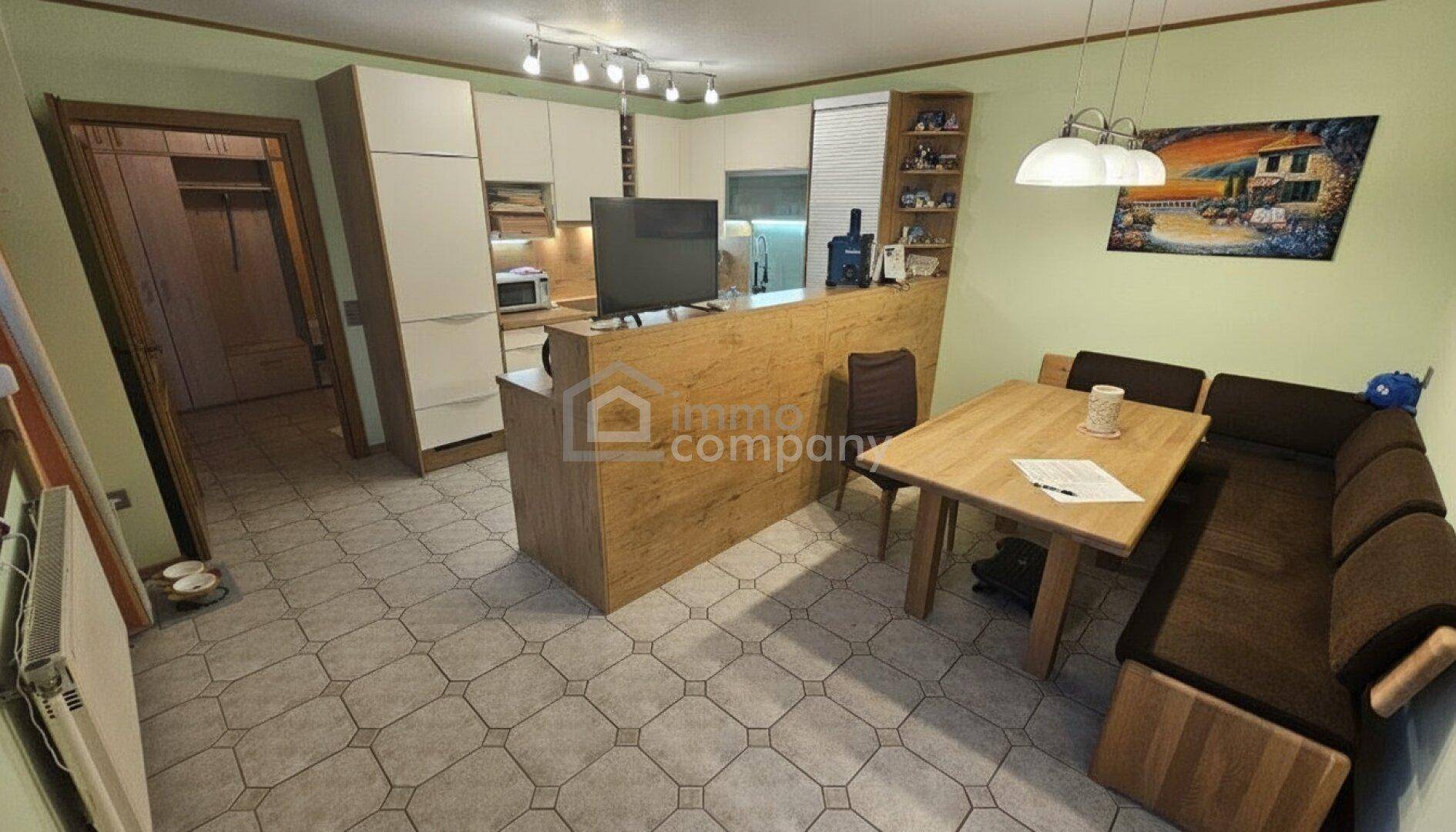 Funktionale Küche mit Essbereich, Fliesenboden und einer Holztheke als Raumteiler.