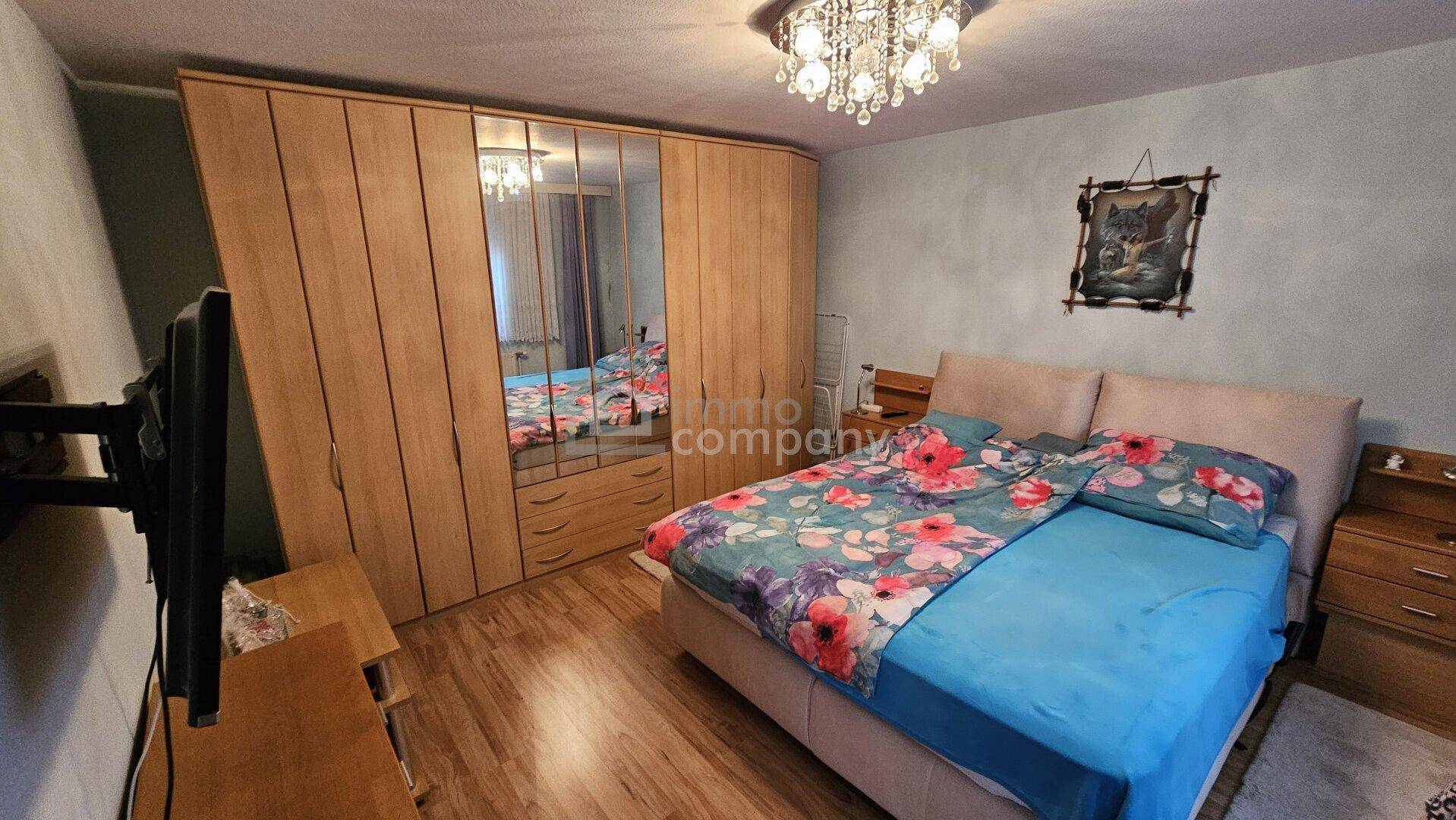 Gemütliches Schlafzimmer mit Laminatboden, großem Kleiderschrank und Doppelbett.