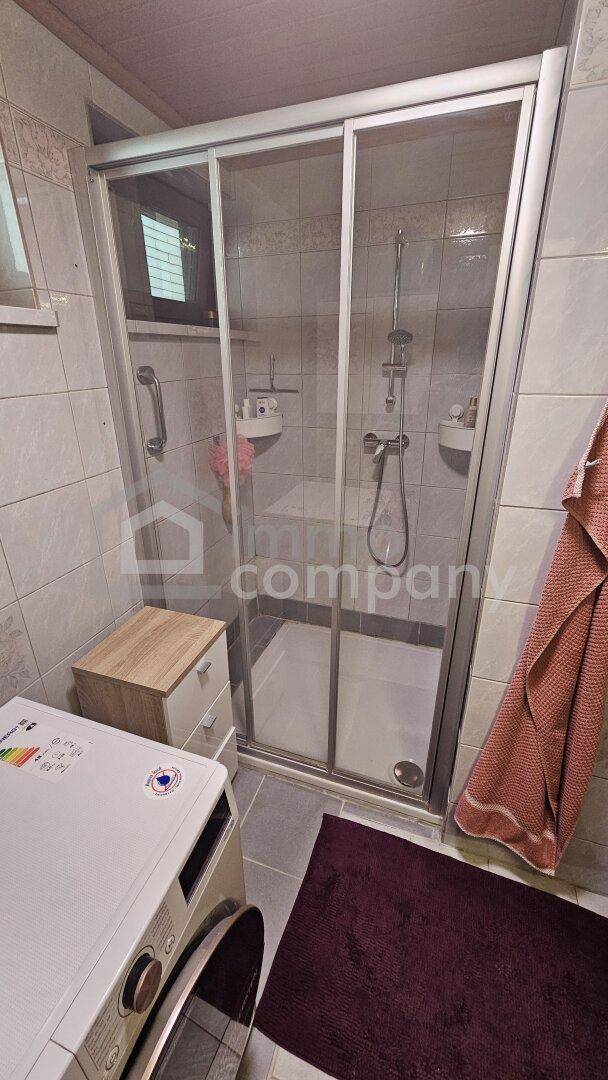 Duschkabine mit Glasschiebetüren und Fliesen an Wänden und Boden im Badezimmer.