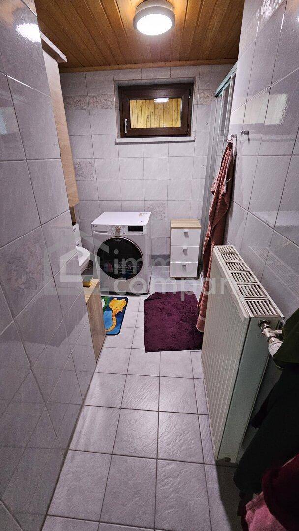 Badezimmer mit Fliesenboden, Waschmaschine und einem Fenster für Tageslicht.