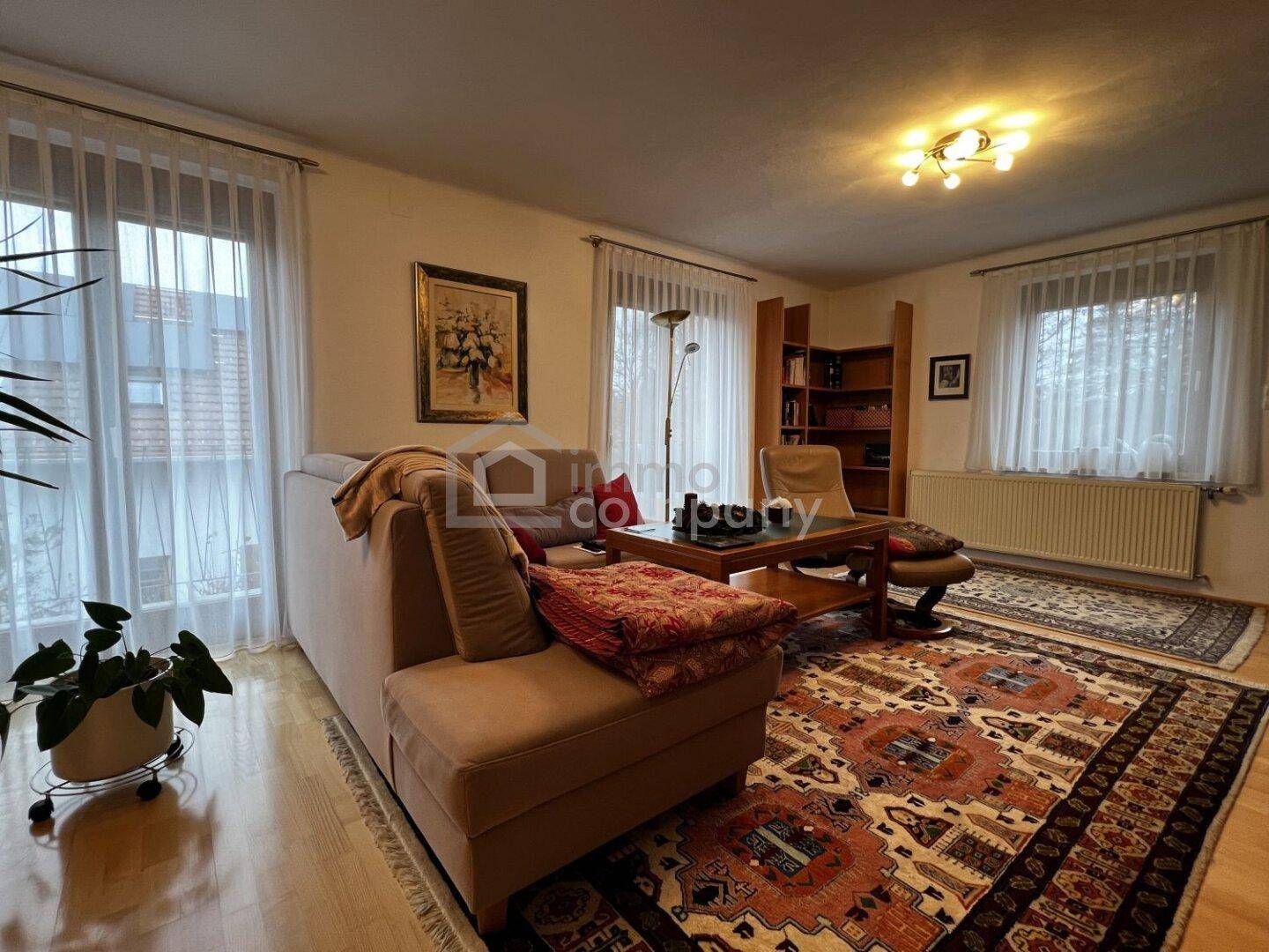 Gemütliches Wohnzimmer mit Parkettboden, Teppich und großem Fenster.