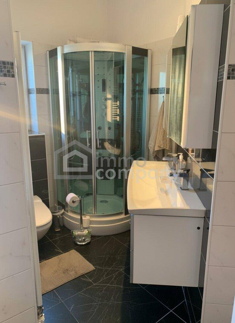 Modernes Badezimmer mit Duschkabine, Einzelwaschbecken und Spiegelschrank über dem Waschtisch.