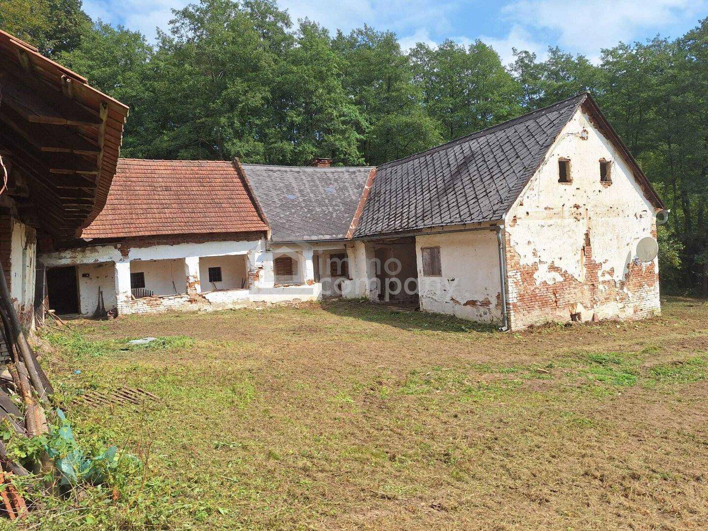 Rückansicht des alten Bauernhauses mit angrenzenden Nebengebäuden und großem Grundstück.