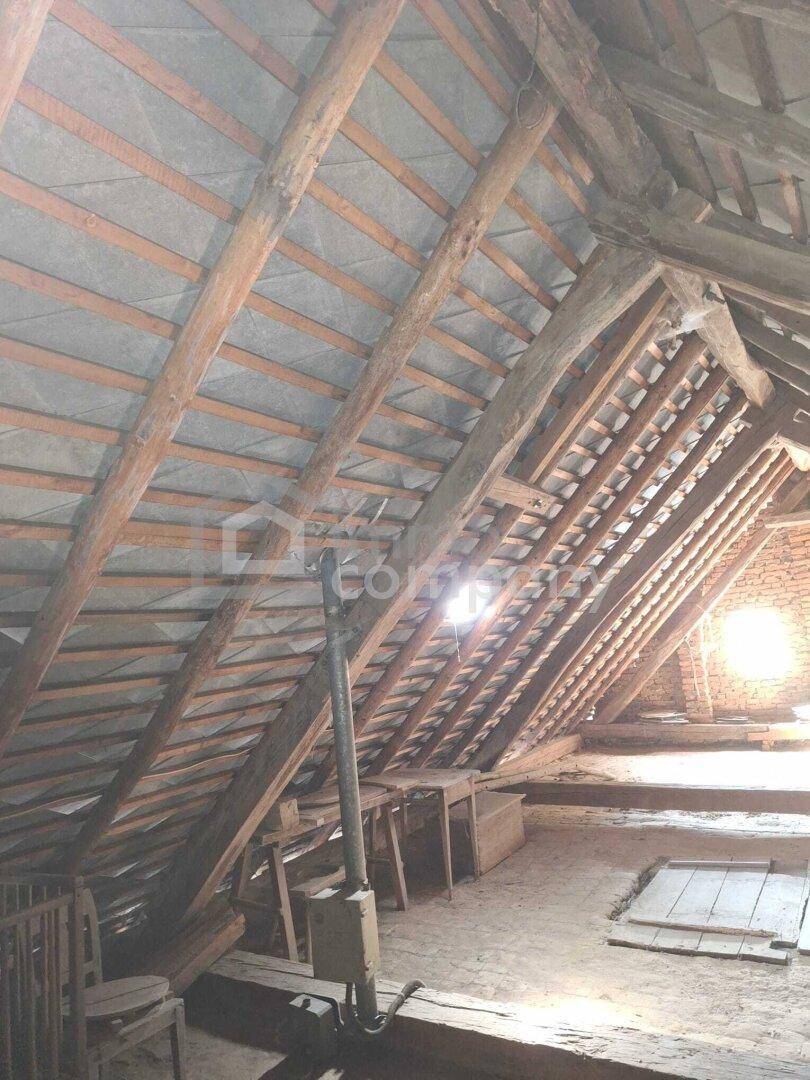 Dachboden mit sichtbarer Holzkonstruktion und natürlichem Lichteinfall durch ein kleines Fenster.