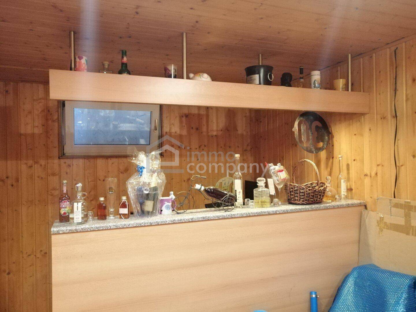 Rustikaler Kellerraum mit Holzverkleidung, Bar und Fenster für Belüftung.