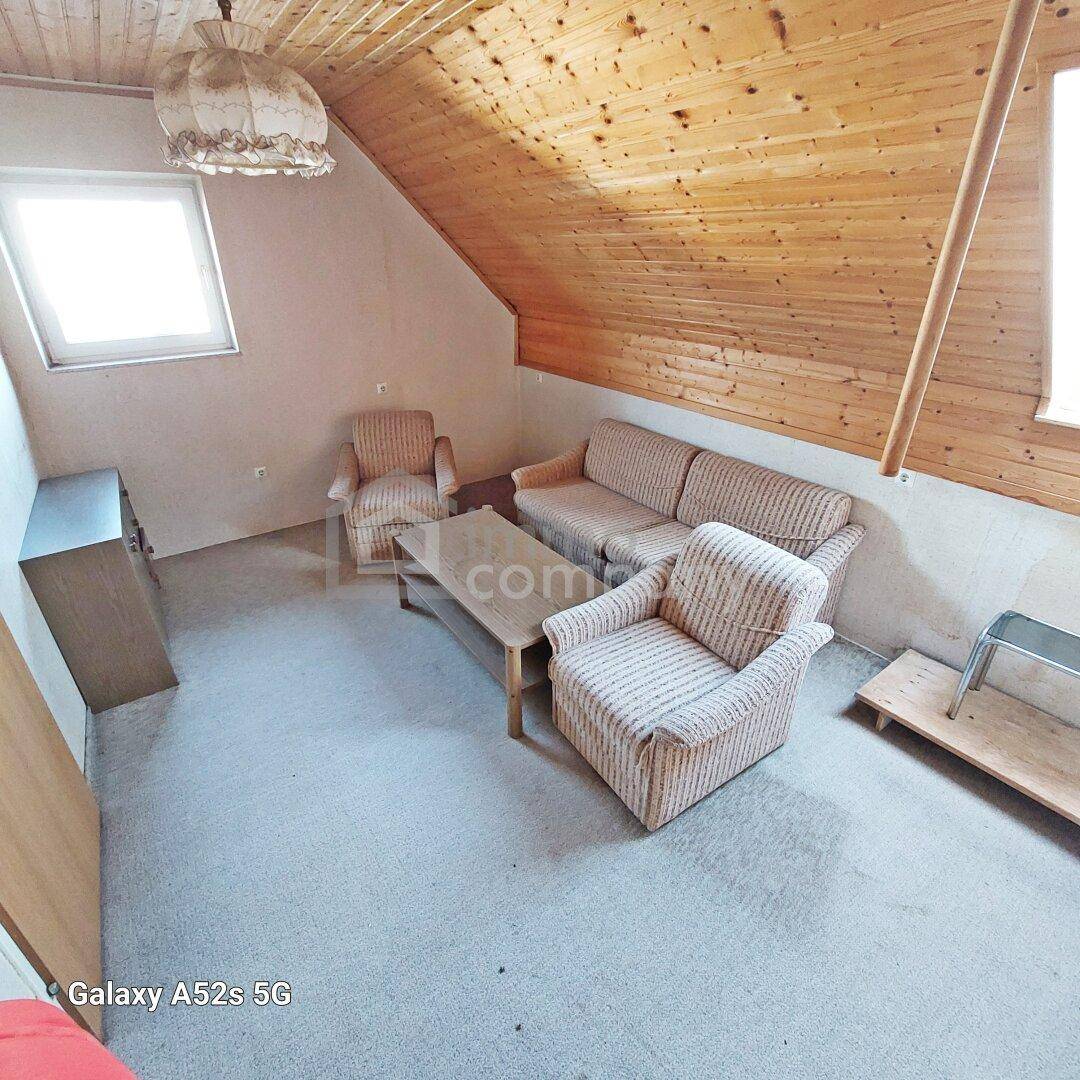 Dachgeschoss-Wohnzimmer mit schrägen Wänden, Holzdecke und Teppichboden.