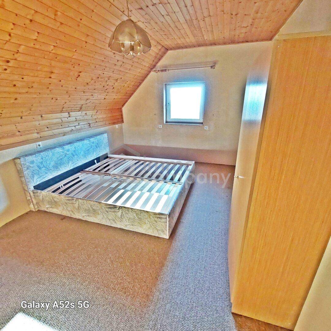 Schlafzimmer im Dachgeschoss mit Holzdachschrägen, Teppichboden und Doppelbett.