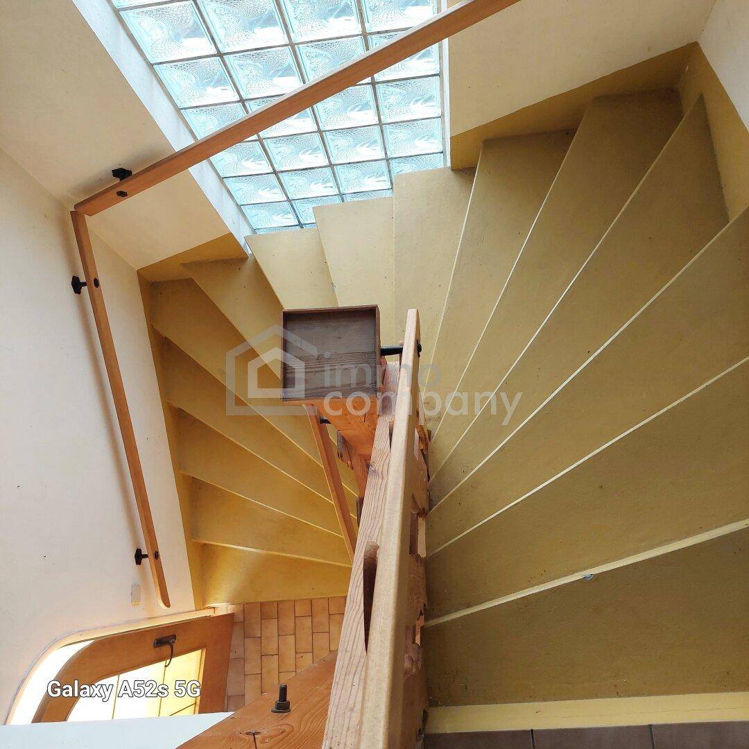 Holztreppe mit Oberlicht aus Glasbausteinen, die viel natürliches Licht hereinlässt.