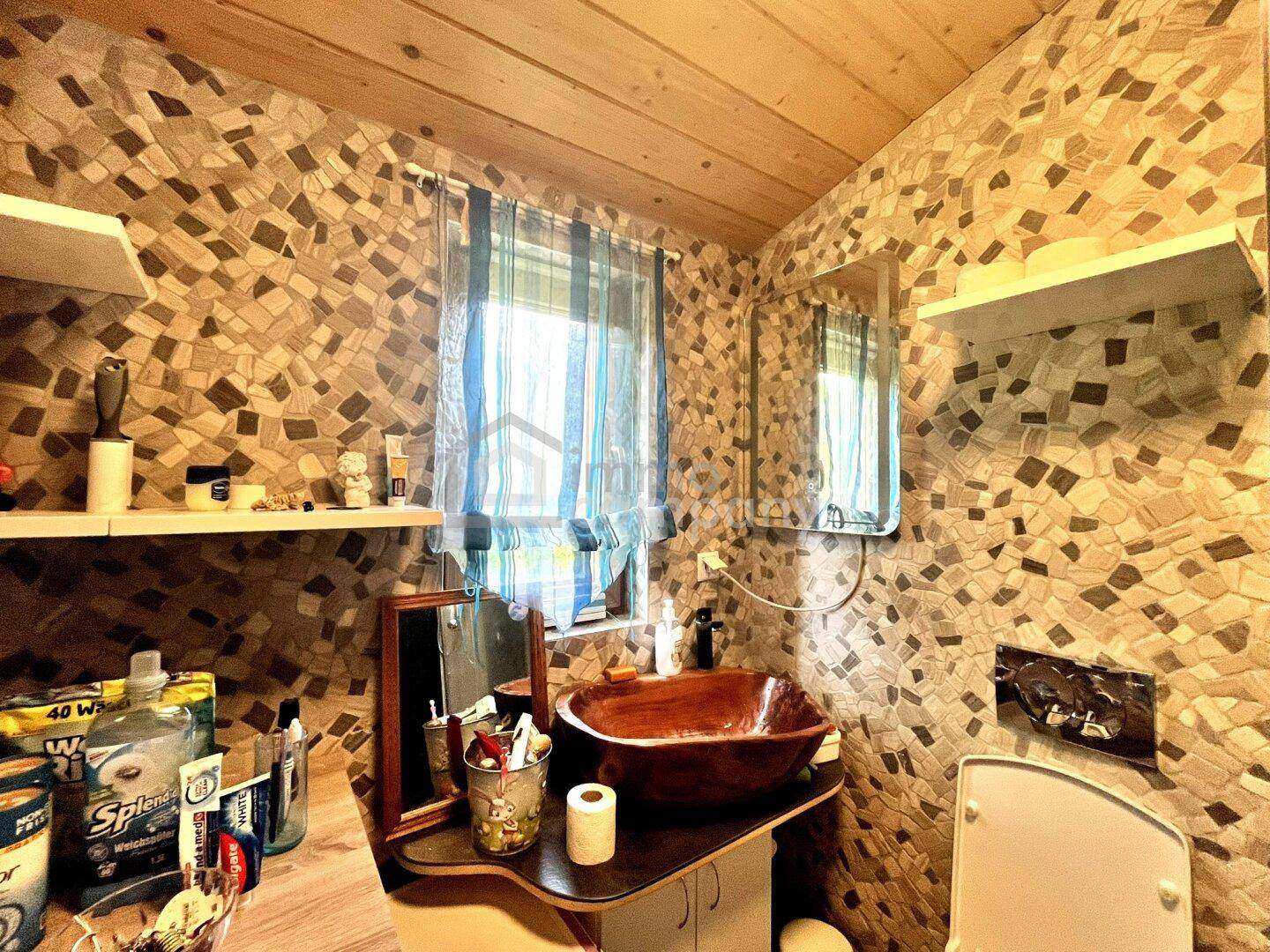 Kleines WC mit auffälliger Tapete, Holzwaschbecken und Fenster für Tageslicht.