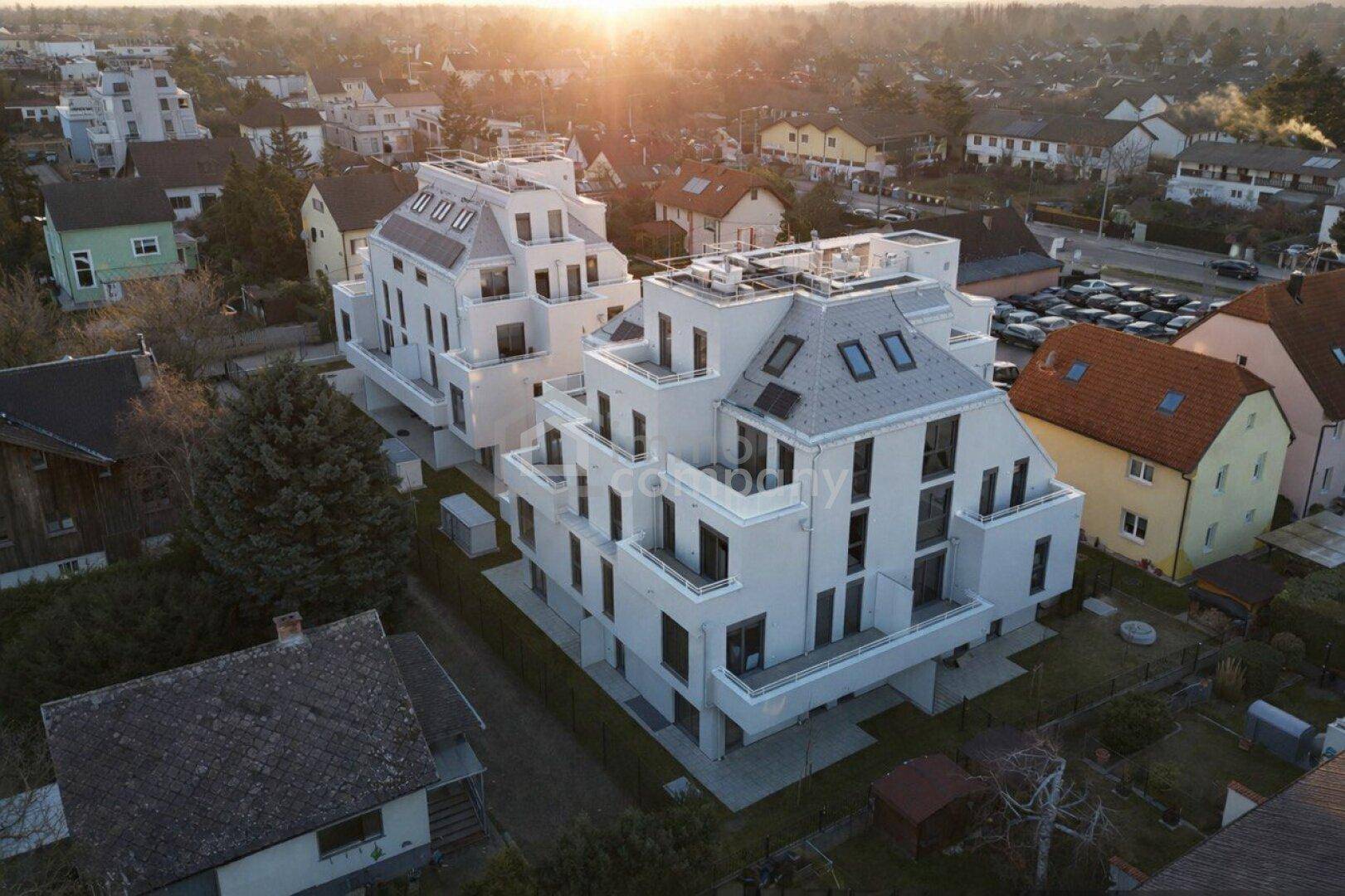 Moderne Neubauten mit gestuften Fassaden und großen Fenstern in einer Wohngegend.
