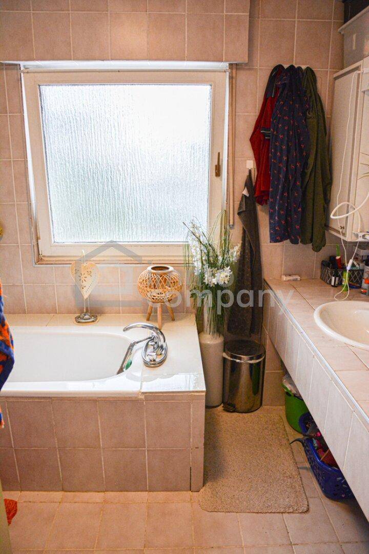 Badezimmer im 80er-Jahre-Stil mit Badewanne, Waschbecken und Fenster.